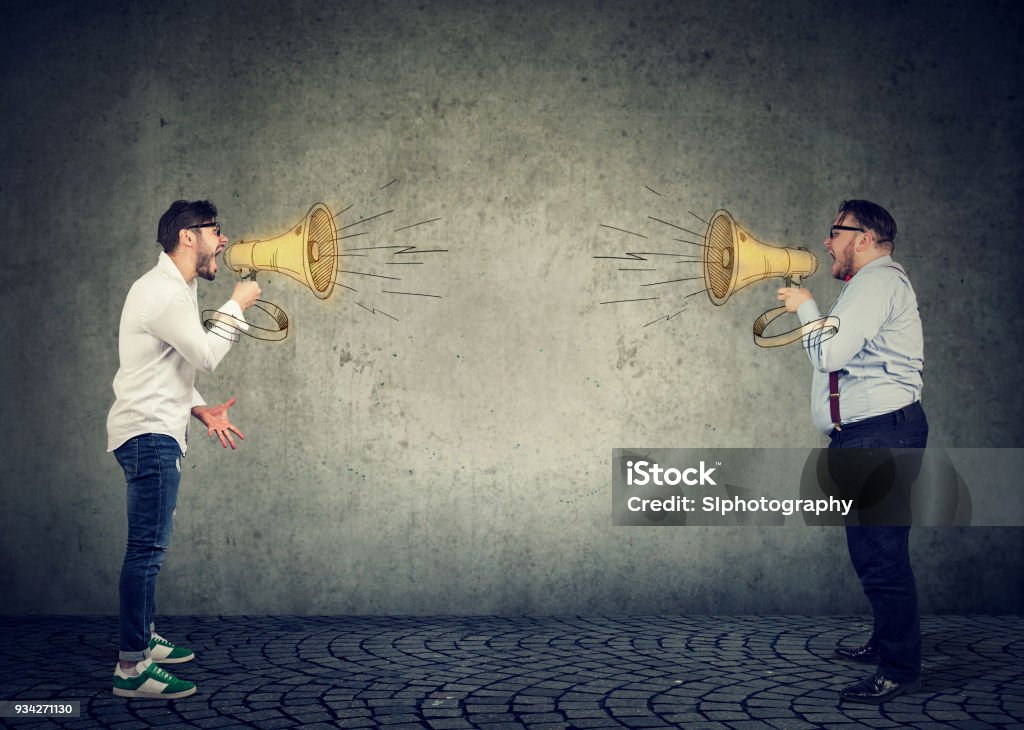 Businessmen screaming into a megaphone at each other Businessmen screaming into a megaphone at each other having an angry debate Arguing Stock Photo
