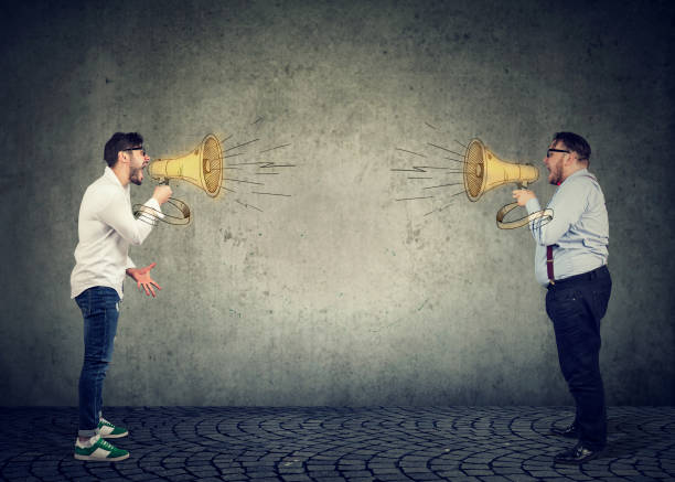 Businessmen screaming into a megaphone at each other Businessmen screaming into a megaphone at each other having an angry debate confrontation photos stock pictures, royalty-free photos & images