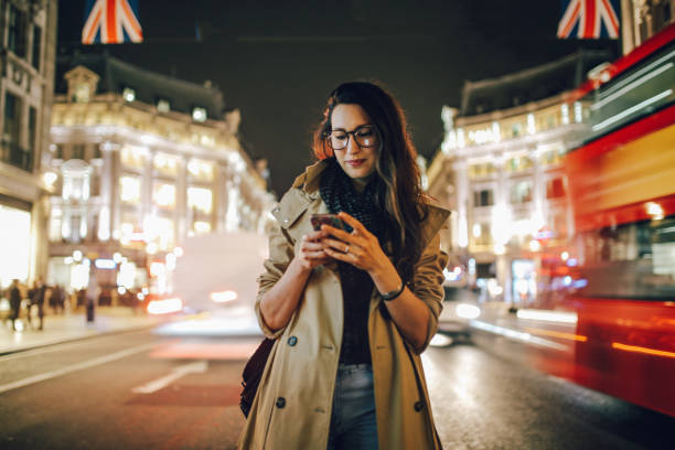 młoda kobieta na ruchliwych ulicach centrum londynu wieczorem, sms-y na telefon komórkowy - london england england street light telephone zdjęcia i obrazy z banku zdjęć