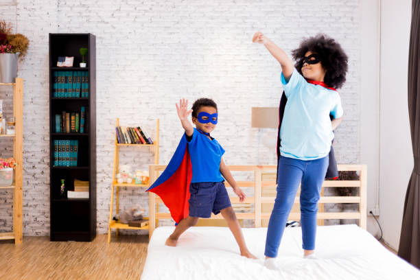 african american happy and confident young kids playing and dressing up as superhero together in bedroom. - bedroom authority indoors home interior imagens e fotografias de stock