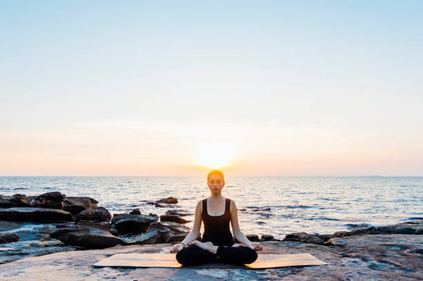 Young woman performs yoga moves on shoreline