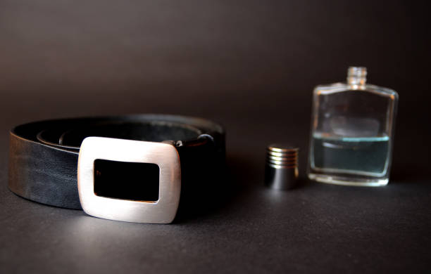 Aftershave and black men belt isolated in dark