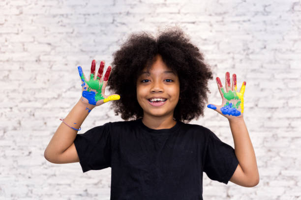 mãos ficando garoto brincalhão e criativo americano africano sujo com muitas cores - fundo de tijolos brancos. - child art paint humor - fotografias e filmes do acervo