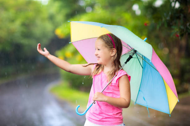 istock Kid with umbrella playing in summer rain. 934289602