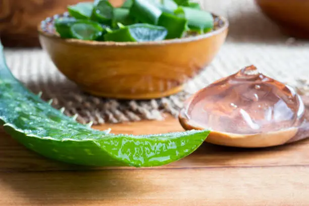 Photo of Aloe vera leaf, with aloe vera gel and slices in the background