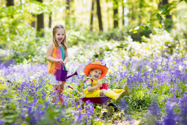istock Kids with bluebell flowers, garden tools 934292908