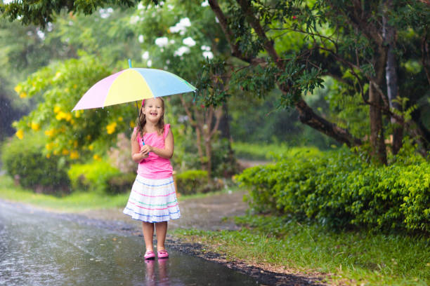 istock Kid with umbrella playing in summer rain. 934295576