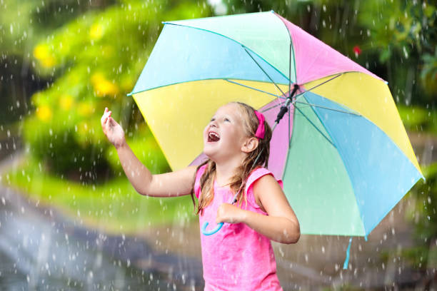 istock Kid with umbrella playing in summer rain. 934301618