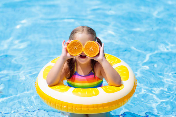 istock Child in swimming pool. Kid eating orange. 934301690