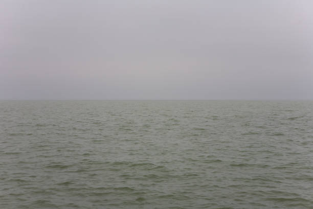 maltempo su un lago con un cielo grigio e senza carattere. immagine semplice per sfondi. - characterless foto e immagini stock