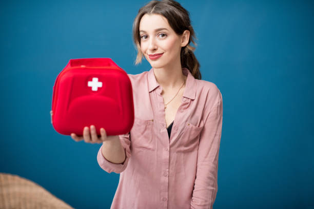 Woman with first aid kit Portrait of a woman with first aid kit on the blue wall background first aid kit wall stock pictures, royalty-free photos & images