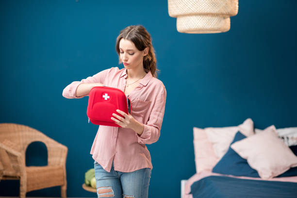 Woman getting a pills from first aid kit Woman getting a pills from first aid kit standing indoors in the blue living room at home first aid photos stock pictures, royalty-free photos & images
