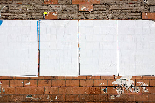 Four real blank billboards on a dilapidated wall Four equal-sized billboards hang on a deteriorating wall.  The billboards do not have any images or text on them, and they are covered with white paper.  The section of the block wall above the billboards is losing most of its red covering, appearing gray with scattered cracks. poster stock pictures, royalty-free photos & images