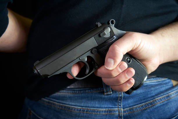 istock Terrorist thief man holding short gun in his hand. Hidden gun on back side body. 934337034