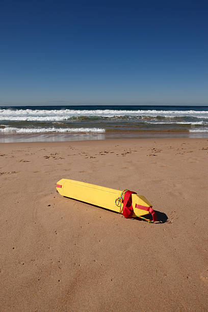 Wide sandy beach with a paddleboard laying on the sand on a sunny day.