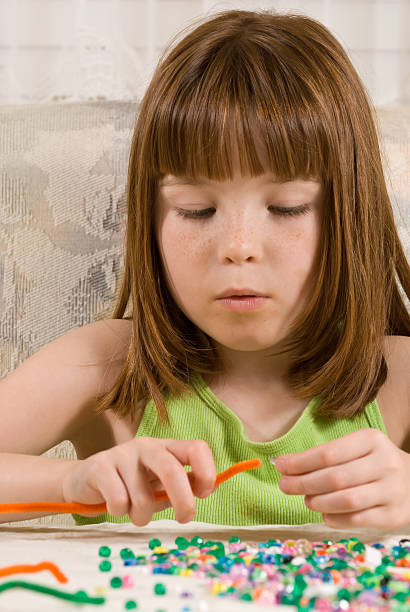 Young girl making a bead bracelet stock photo
