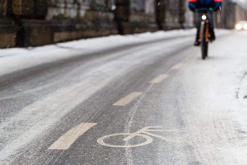 A snow-capped bike path and a partial view of a cyclist