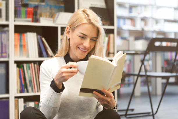istock Young woman at the library enjoying book with coffee 934416936