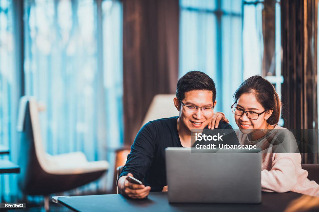 Young Asian married couple working together using laptop at home or modern office with copy space. Startup family business, SME entrepreneur, business partner, love relationship, or freelance concept Couple - Relationship Stock Photo