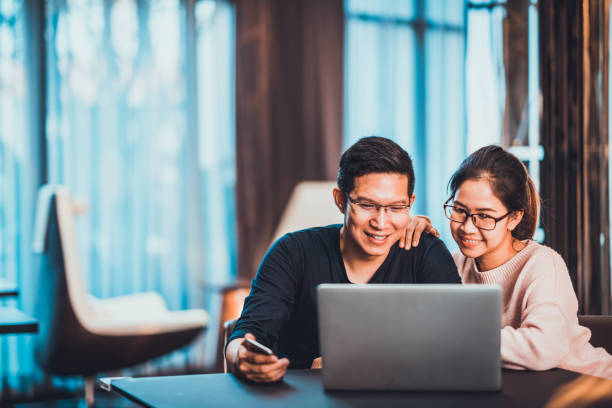 Young Asian married couple working together using laptop at home or modern office with copy space. Startup family business, SME entrepreneur, business partner, love relationship, or freelance concept Young Asian married couple working together using laptop at home or modern office with copy space. Startup family business, SME entrepreneur, business partner, love relationship, or freelance concept chinese couple stock pictures, royalty-free photos & images