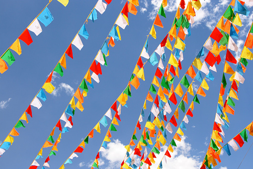 Multicoloured flags flying in a strong wind against a blue, cloudy sky