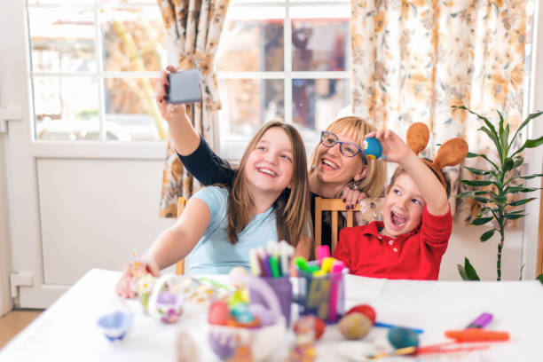 istock Happy mother with children painting Easter eggs at home 934437136