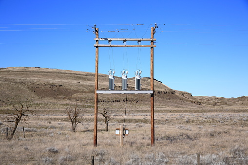 Wooden electricity pole with transformers in desert