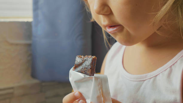 Close-up portrait of little child girl eats the fruit muesli bar stock photo
