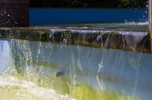 Fountain in city park on hot summer day, beautiful bright streams of sparkling water, drops and splashes.