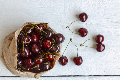 Fresh cherry berries in a paper bag, isolated on a white background. Concept of healthy and healthy nutrition.