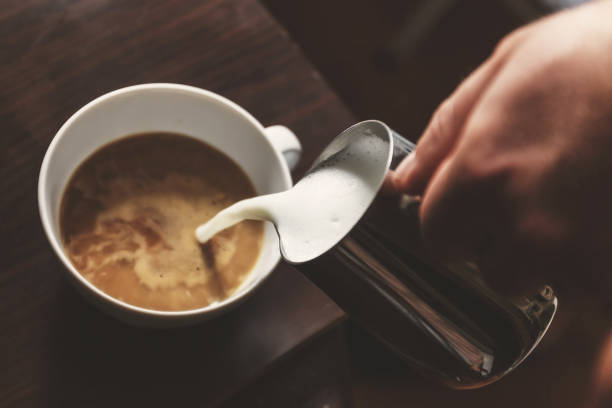 istock man pouring into a cup of coffee with milk 934492222