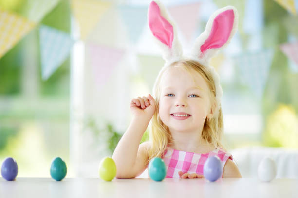 istock Cute little girl wearing bunny ears playing egg hunt on Easter 934492828