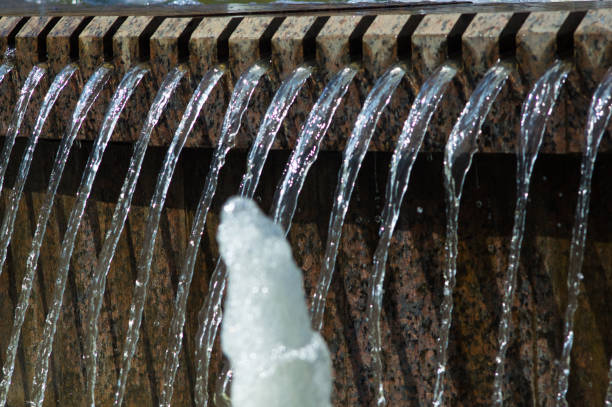 Fountain in city park on hot summer day, beautiful bright streams of sparkling water, drops and splashes.