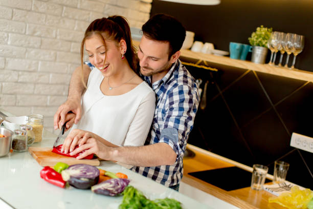 istock Young couple have fun in modern kitchen indoor while preparing vegetables food for lunch 934506654