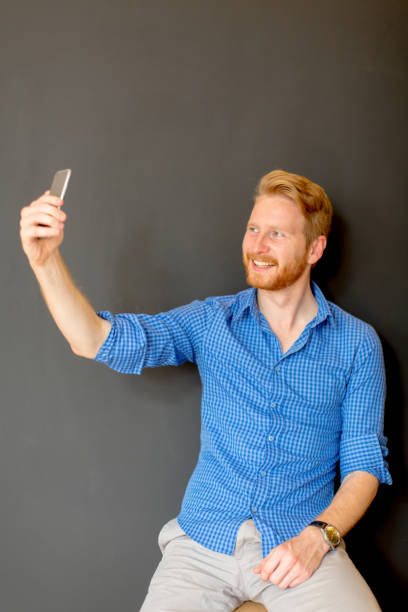 istock Ginger man taking selfie isolated on black 934506696