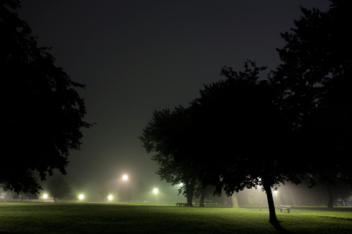Man walking alone down a city street sidewalk on a foggy night. in Kingston, Ontario, Canada
