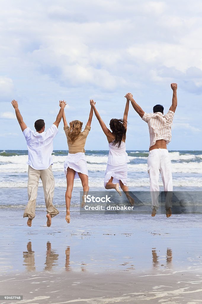 Quatro jovens, Dois Casais, saltar em celebração na praia - Royalty-free Praia Foto de stock