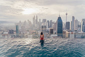 Woman in the swimming pool with view of Kuala Lumpur