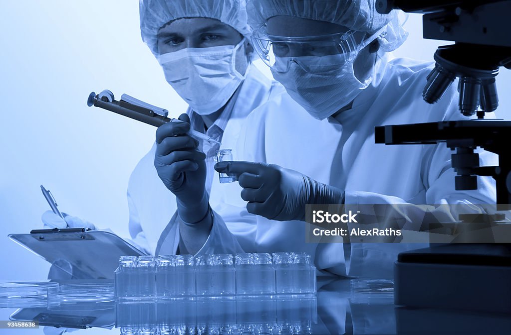 Close-up of two workers with hygienic wear at a laboratory student or intern overseeing the work of scientists in the laboratory. Adult Stock Photo