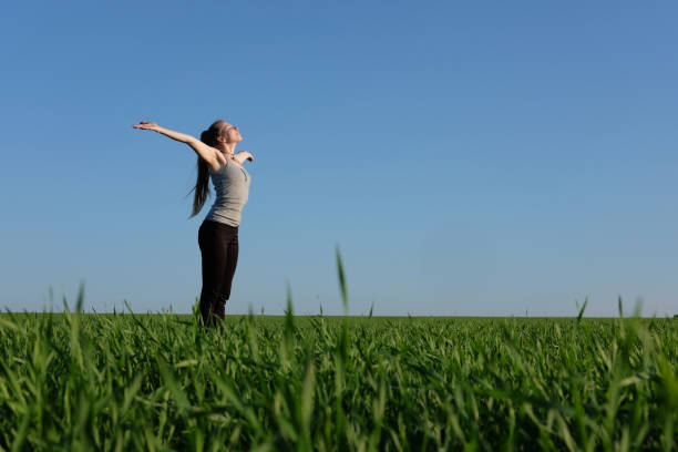 istock girl stretching herself in green field with blue sky background 934607680
