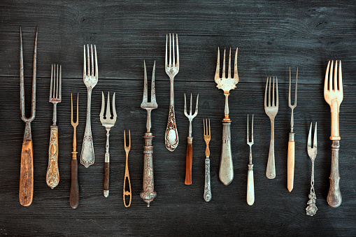 Top view on various forks, old utensils. Flat lay on rustic  dark wooden background. Antique kitchenware background