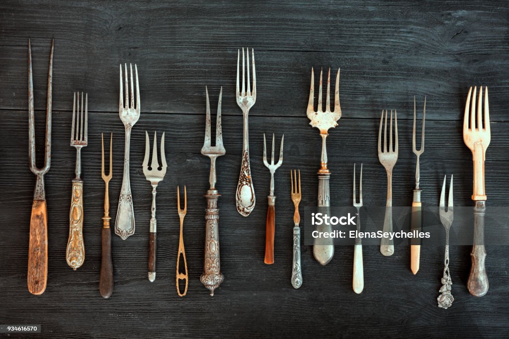 Top view on various forks, old utensils. Flat lay on rustic  dark wooden background. Antique kitchenware background Antique Stock Photo