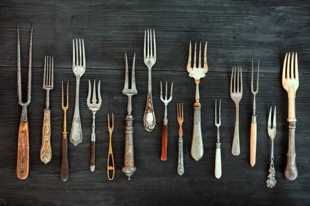 Top view on various forks, old utensils. Flat lay on rustic  dark wooden background. Antique kitchenware background
