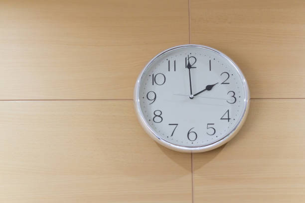 istock white steel clock on light wooden wall, show time 2 PM 934619556