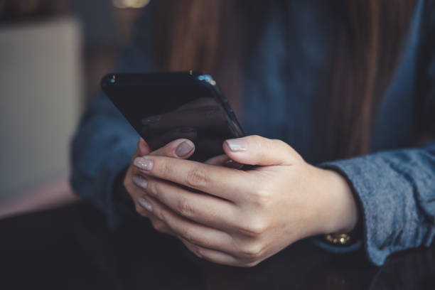 istock Closeup image of a woman holding , using and looking at smart phone on table 934637150