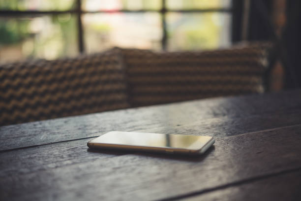 istock A smart phone on wooden table with blur background 934637336