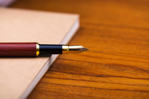 istock Fountain pen or ink pen with notebook paper on wooden working table with copy space, office desk concept. 934643194