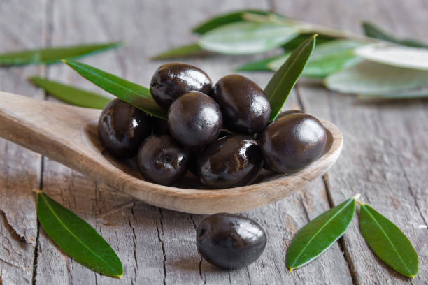Fresh black olives on a wooden spoon