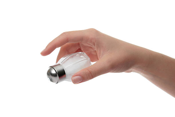 istock Female hand sprinkling salt shaker on white background 93466178