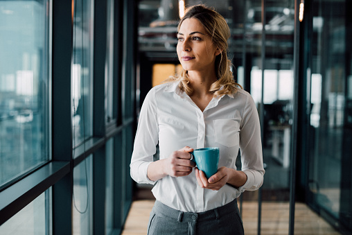 Thoughtful businesswoman looking away with cup of coffee